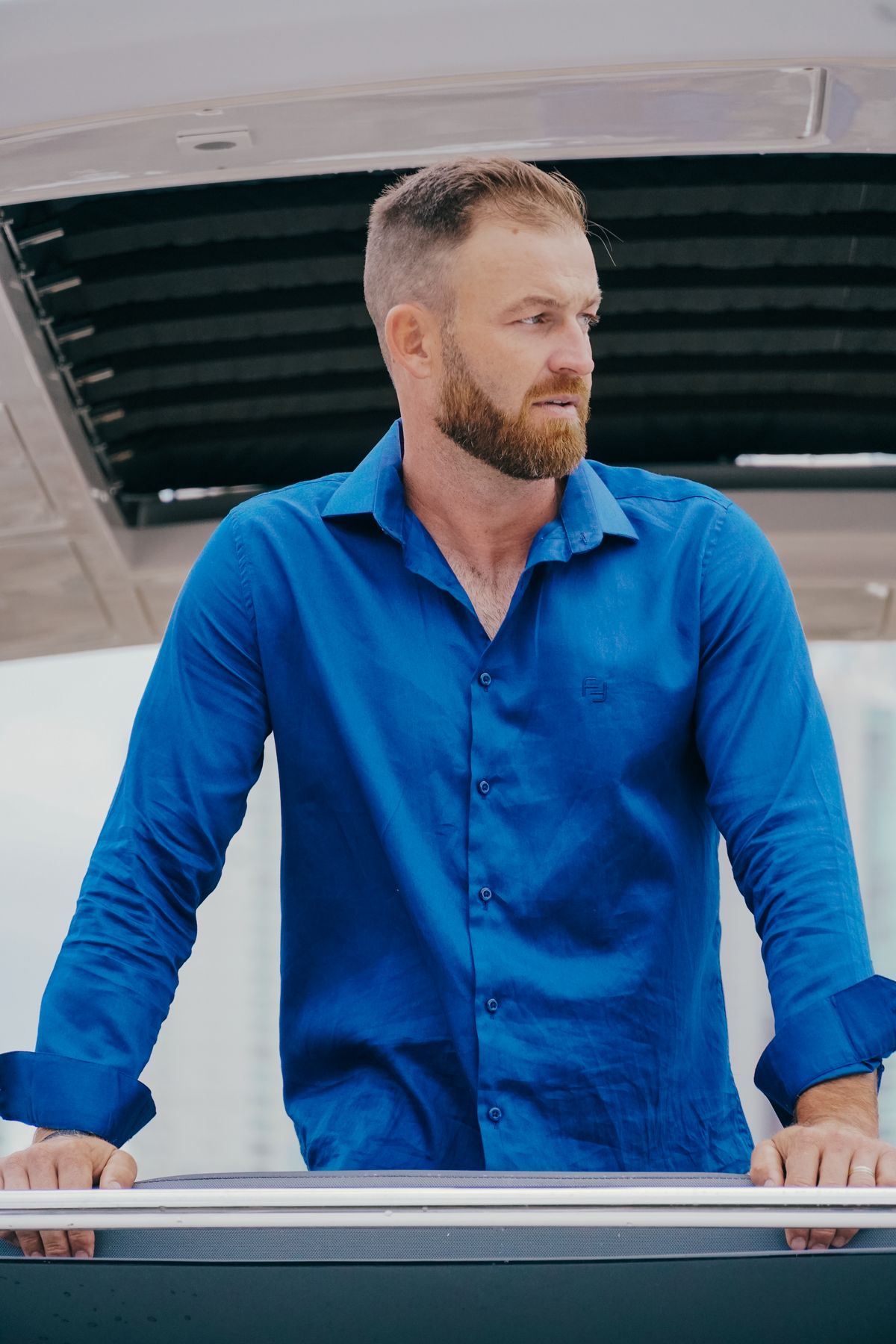 Homem de camisa azul Fortwo apoiado no guarda-corpo de um iate